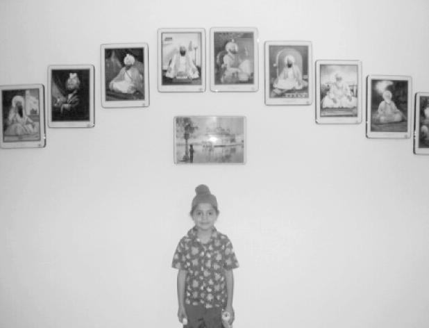 Gurusewak's younger son at home with photos of Sikh Gurus